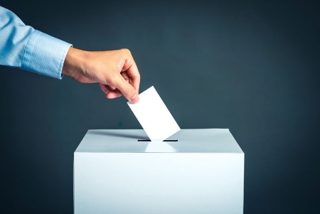 Person placing vote card in ballot box