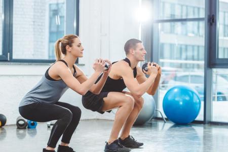 Man and woman exercising hard at gym